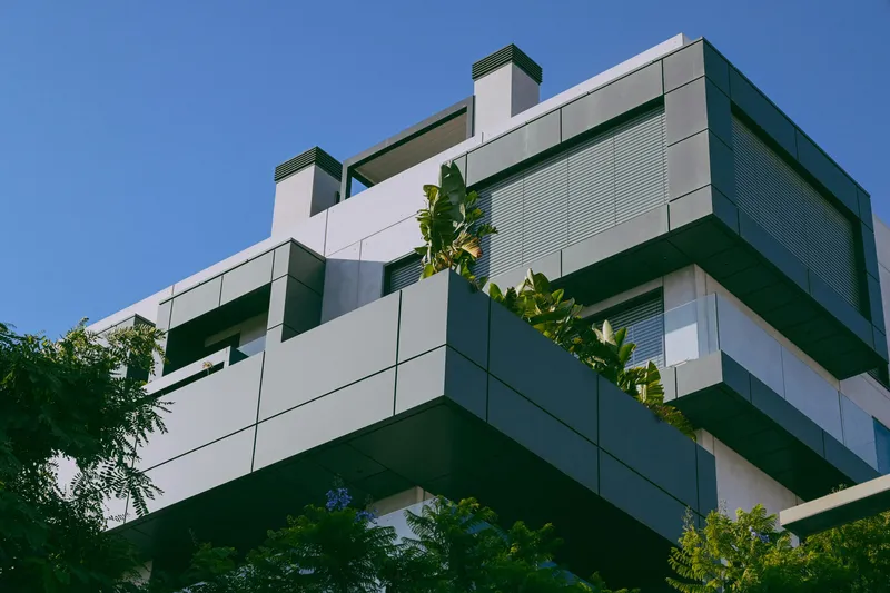 Yeşil-gri alüminyum kompozit panel kaplı, balkonlu modern apartman cephesi